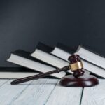 Gavel in front of books on gray background_s
