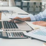 Man working at a computer with finance docs_s