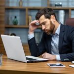 man in business suit with glasses and beard using laptop for work