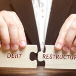 man collects wooden blocks with the word Debt Restructuring_s