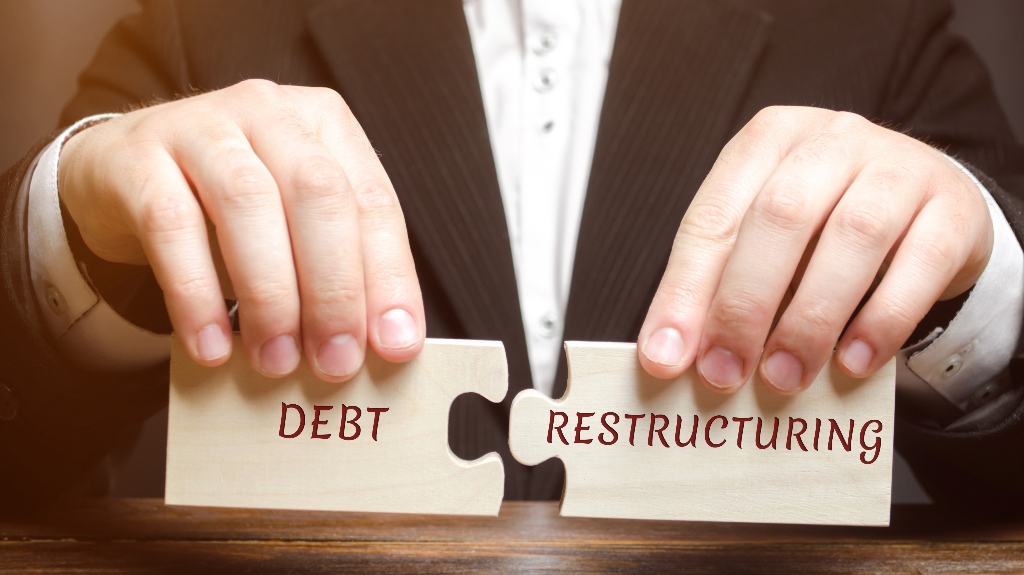 man collects wooden blocks with the word Debt Restructuring