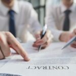 Man is pointing a finger at one clause in a contract_s