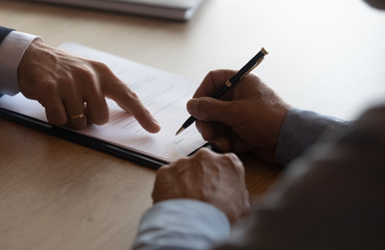 Hands of lawyer pointing where to sign document