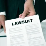 a lawyer in his office showing a document with the text lawsuit written in it_s